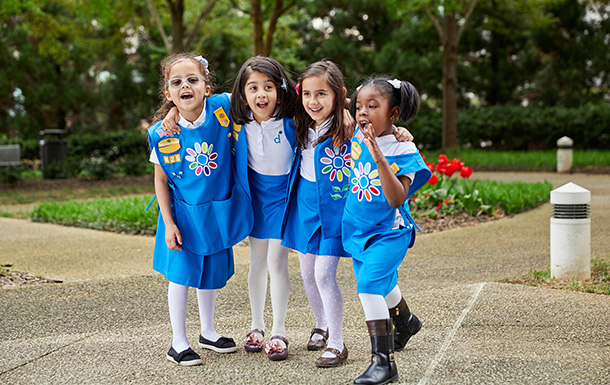 Group of girl scout daisies hugging and smiling at camera.