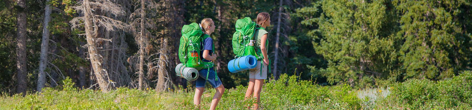  dos niñas caminando por el bosque con mochilas 